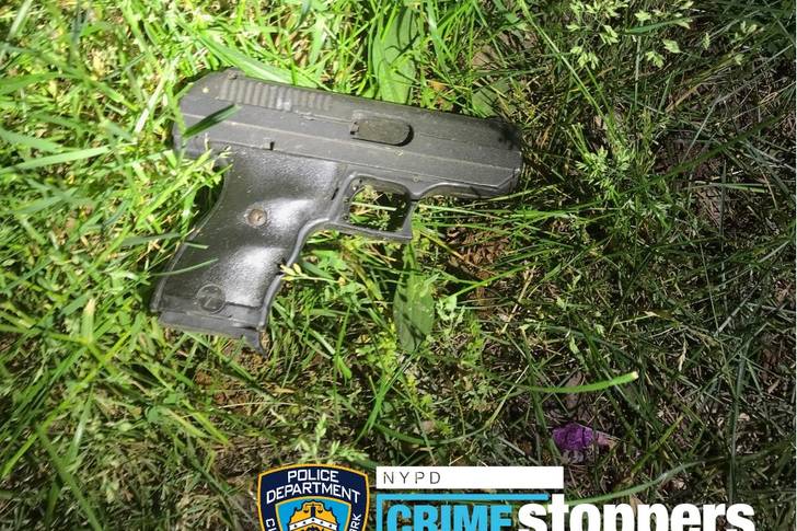 A firearm recovered at the scene of a shooting is found on a bed of grass.